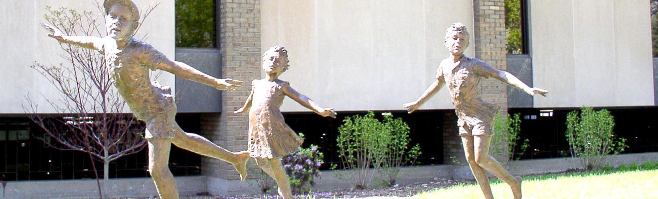 photo of statue outside the library of three children playing