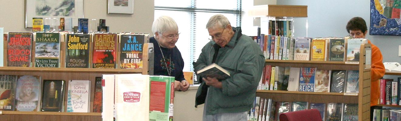 Photo of staff and customer looking at books in the reading room