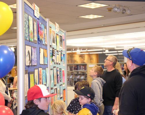 Students, Families and Teachers look at Art created by students that are on display inside the Arlington Heights Memorial Library
