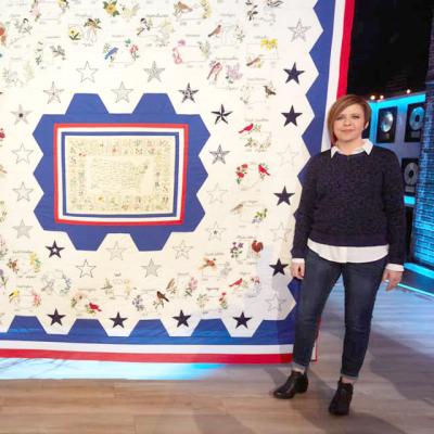 Shannon Downey standing in front of the completed Rita's Quilt