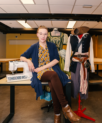 Lisa Hale sits at the Makerplace with several of her cosplay designs showcased behind her