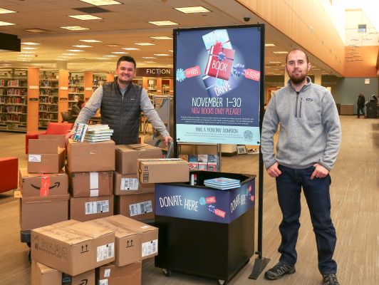 Two People surrounded by boxes filled with donations