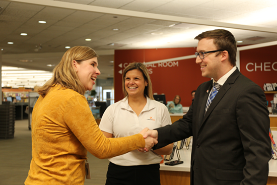 Three networkers smile and engage in conversation at the library.